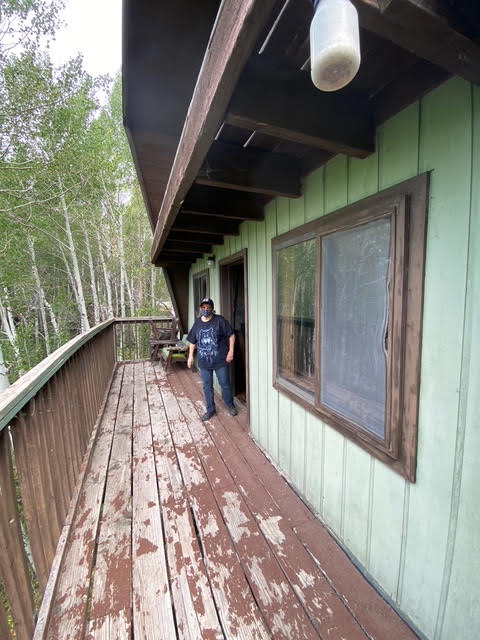 The cabin's original deck with peeling paint and worn railings