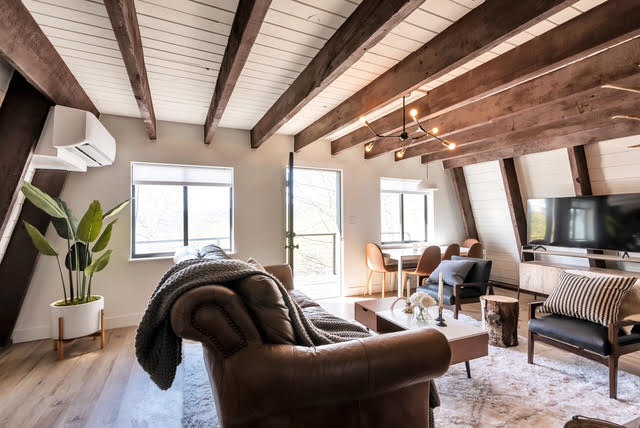 The renovated family room with vaulted wood-beam ceilings and new furnishings