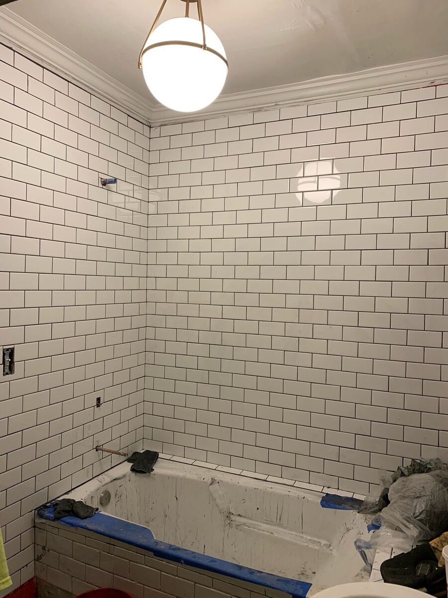 The bathroom mid-renovation with new white subway tile being installed