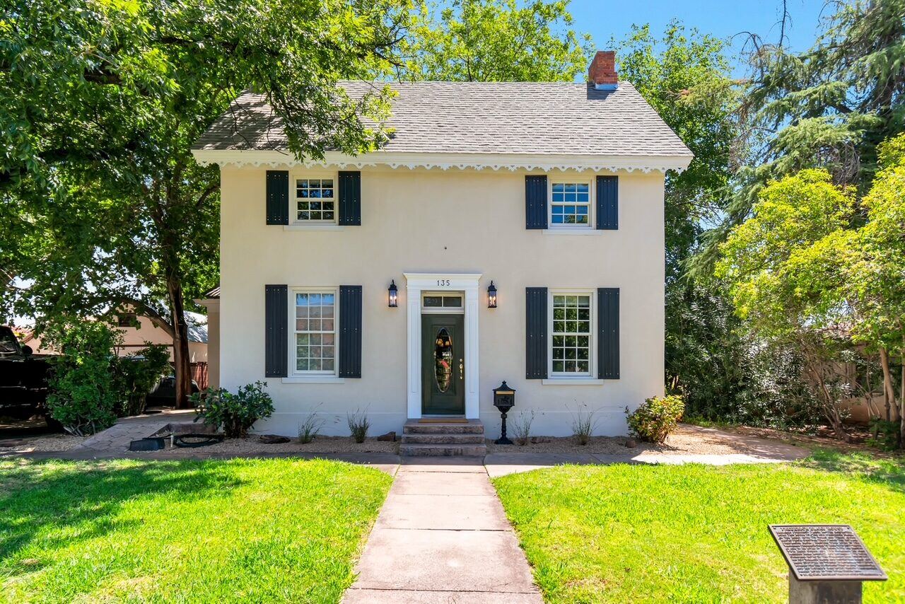 The restored historic home's exterior, with fresh paint, shutters, and landscaping