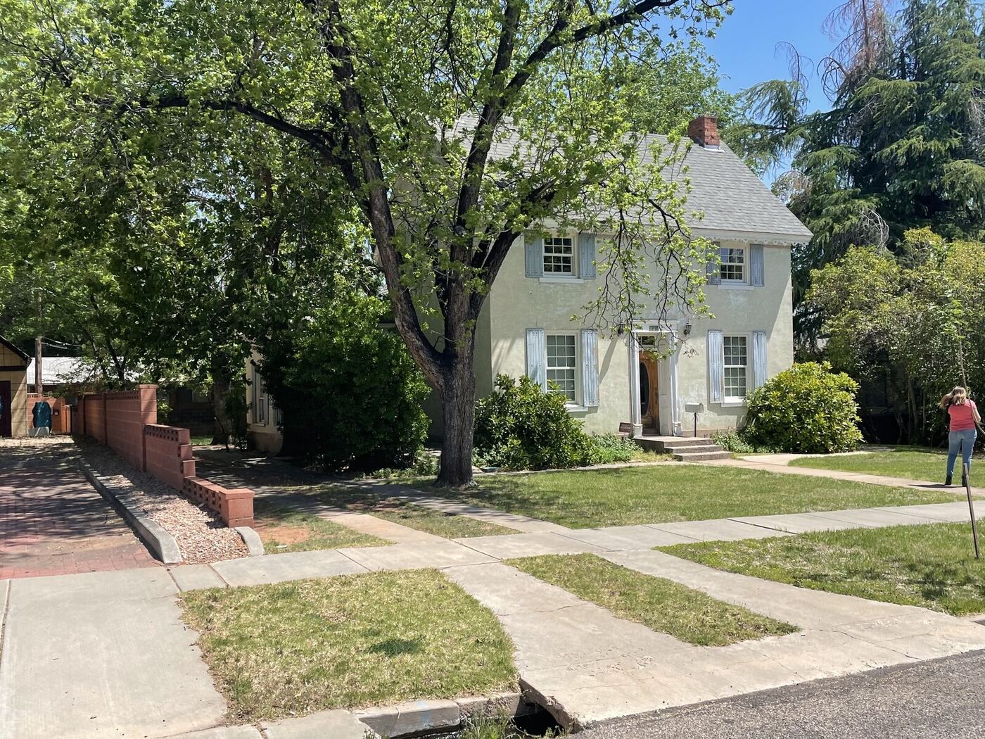 The historic home's exterior before the deal, with an overgrown tree and worn landscaping