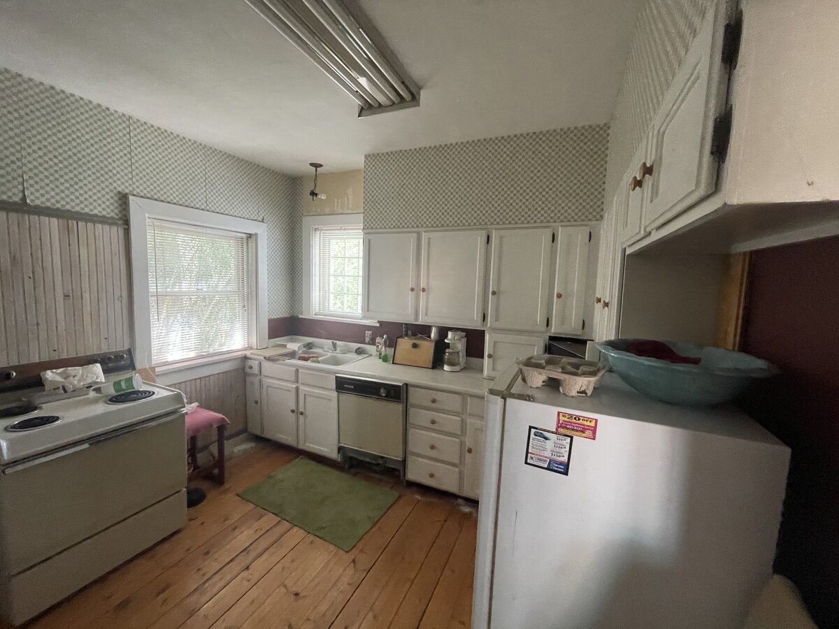 The home's original dated kitchen with worn cabinetry and appliances