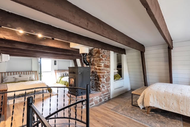 The finished loft space with beds and a wood-burning stove
